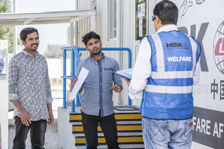 Workers interacting with a Workers’ Welfare Officer at the Lusail Stadium accommodation site